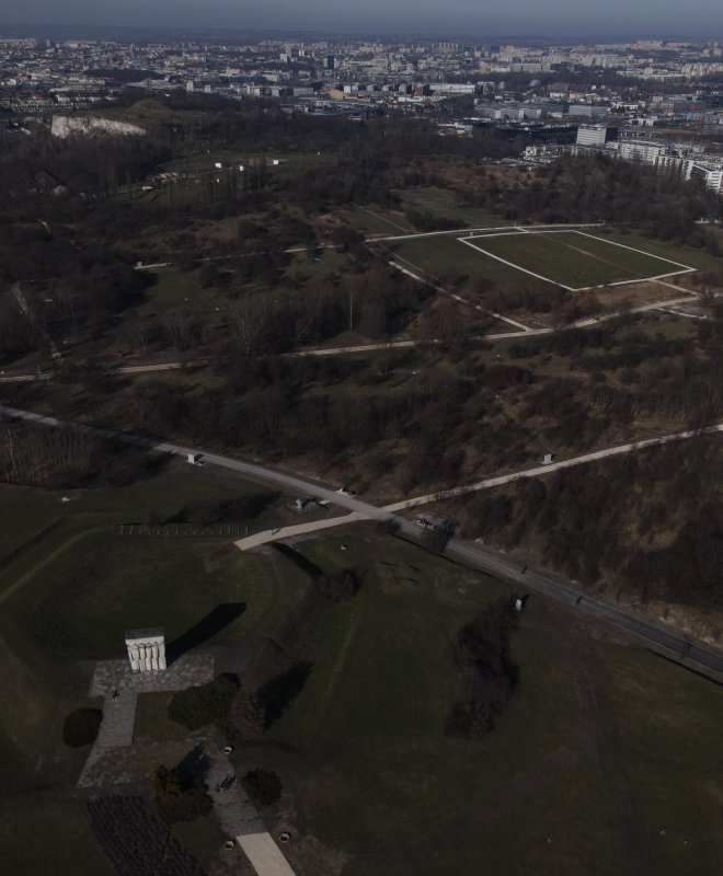 Zdjęcie wszpółczesne, kolorowe, wykonane z drona. Na zdjęciu widok Pomnika Ofiar Faszyzmu oraz rolełego terenu byłego obozu Plaszow.